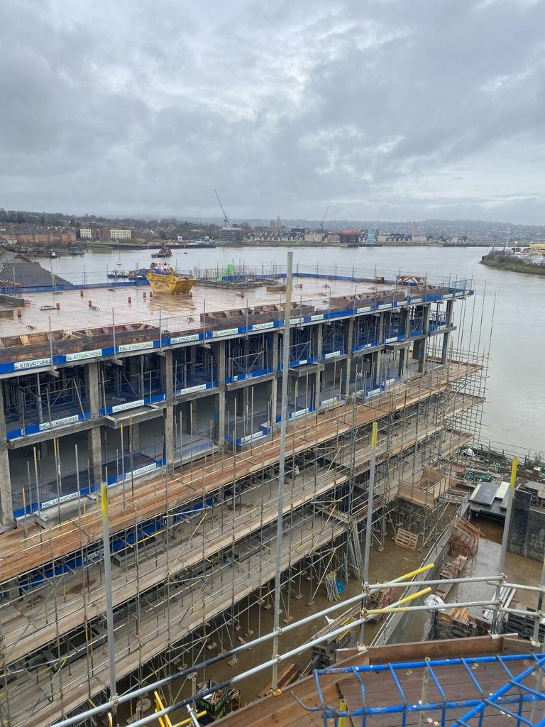 Reinforced-concrete frame on a riverside development in Chatham: piled foundations, ground-floor slab with reinforcement, columns, walls and upper floors cast in situ.