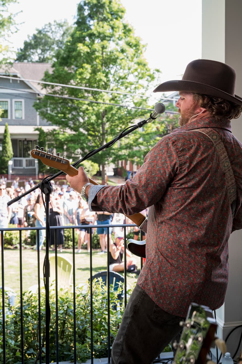A musician plays the guitar and sings for a crowd at Porchfest.