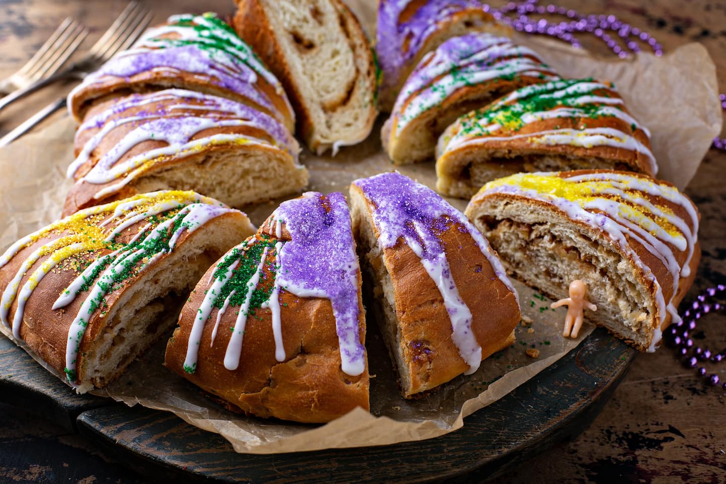 A Mardi Gras king cake is sliced and ready to eat.