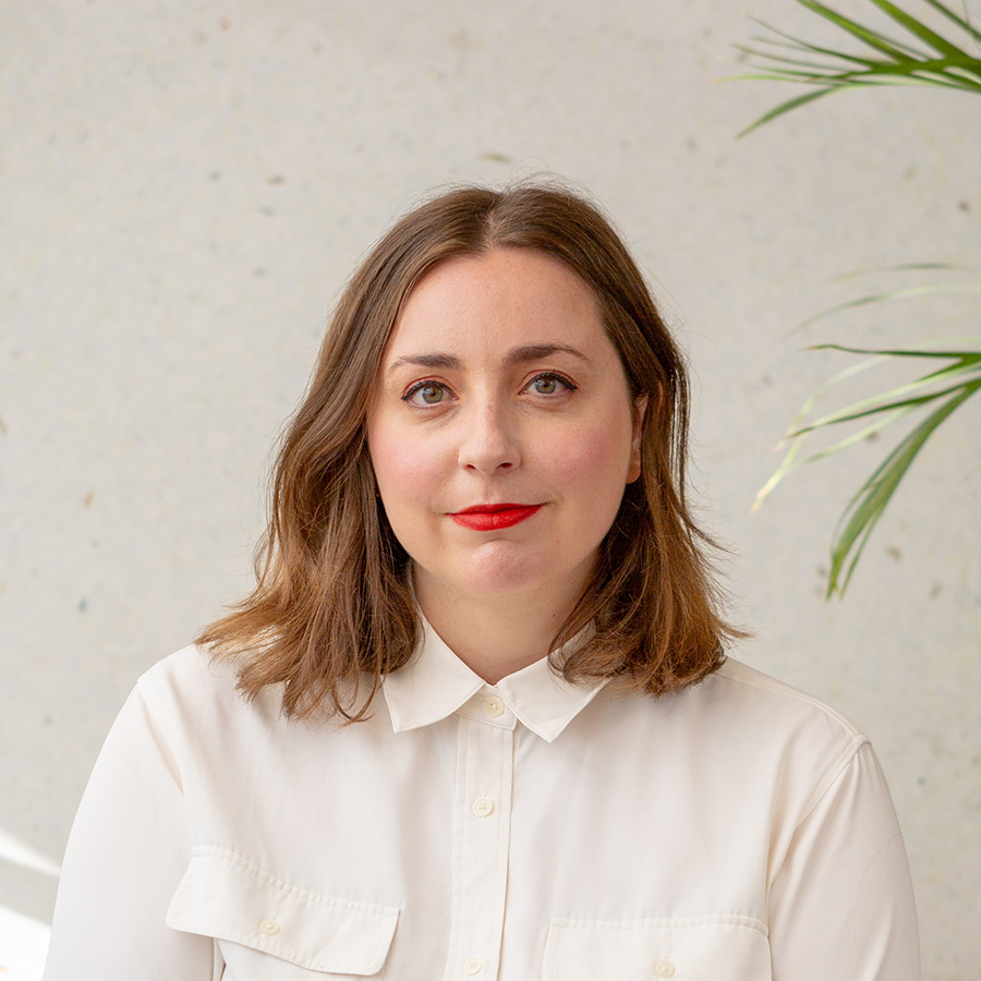 Léa Berger looking slightly upward, wearing a cream shirt with red lipstick.