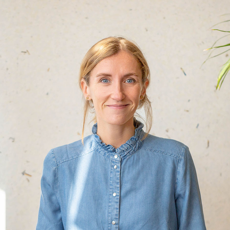 Juliette Bouilly smiling, wearing a denim shirt with hair pulled back.