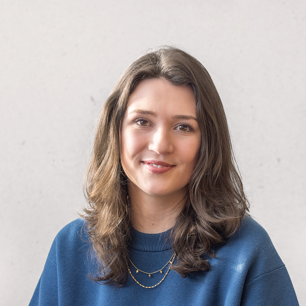 Ellie wearing blue jumper with long brown hair smiling at the camera