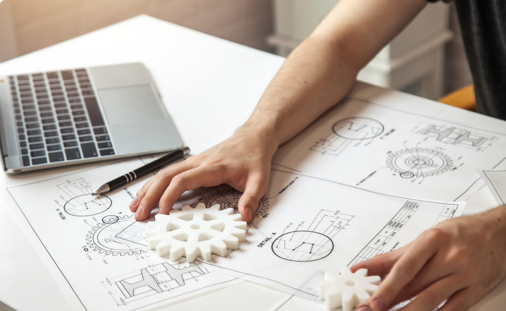 Engineer man hands on table with engineering drawings and laptop