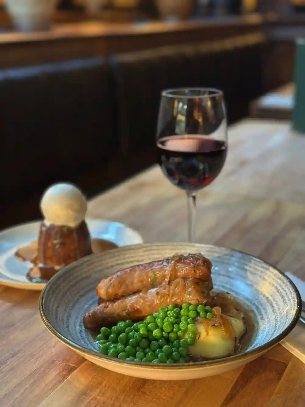 When the weather turns grim, retreat somewhere better.
Plump sausages over buttery mash with sweet peas and a rich gravy, paired with a generous glass of red — and a warm Sticky toffee pudding to follow.
A little comfort, done properly. 🍷
