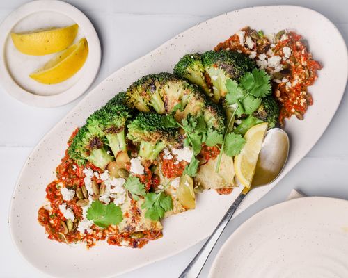 Broccoli steaks on a platter with romesco sauce