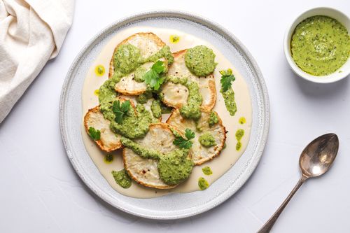 Serving plate of celeriac steaks with salsa drizzled on top