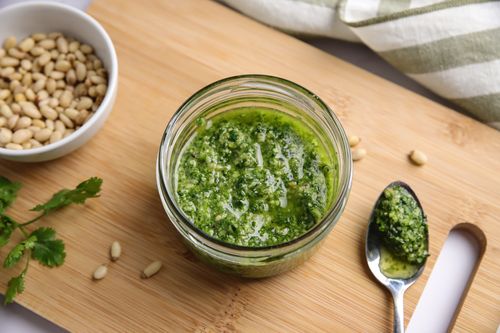 Jar of coriander pesto on wooden board
