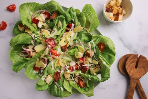 Serving platter of green salad topped with tomatoes and croutons
