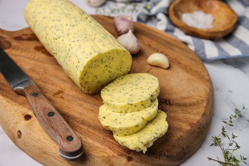 Log of garlic butter on a wooden board