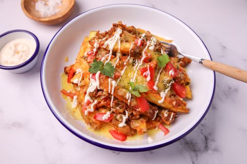 Serving bowl of loaded chili fries drizzled in sauce