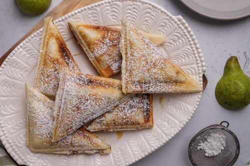 Golden spiced pear hand pies dusted with icing sugar, fresh from a toastie maker - a delicious food rescue twist on dessert.