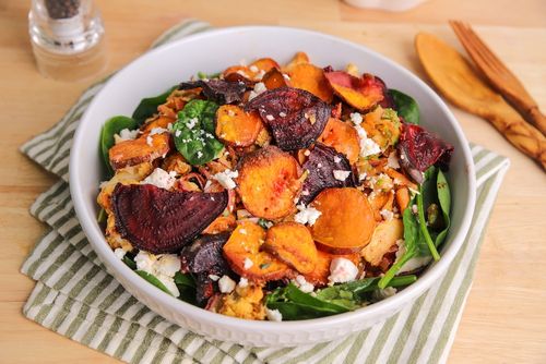 Crispy kumara and beetroot slices on a seasonal salad with spinach, roasted cauliflower, walnuts, and feta – a vibrant autumn dish.