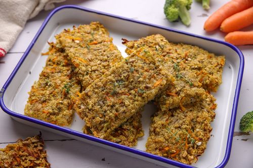 Homemade savoury flapjacks packed with grated broccoli and carrot, fresh from the oven and cut into golden squares.