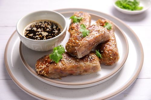 Crispy rice paper rolls filled with a vibrant mix of tofu, cabbage, and shredded veggies, served with a tangy dipping sauce.