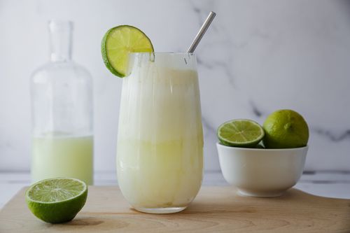 Blended Brazilian lemonade (limonada suíça) served in a glass over ice, with visible lime flecks and creamy froth on top.