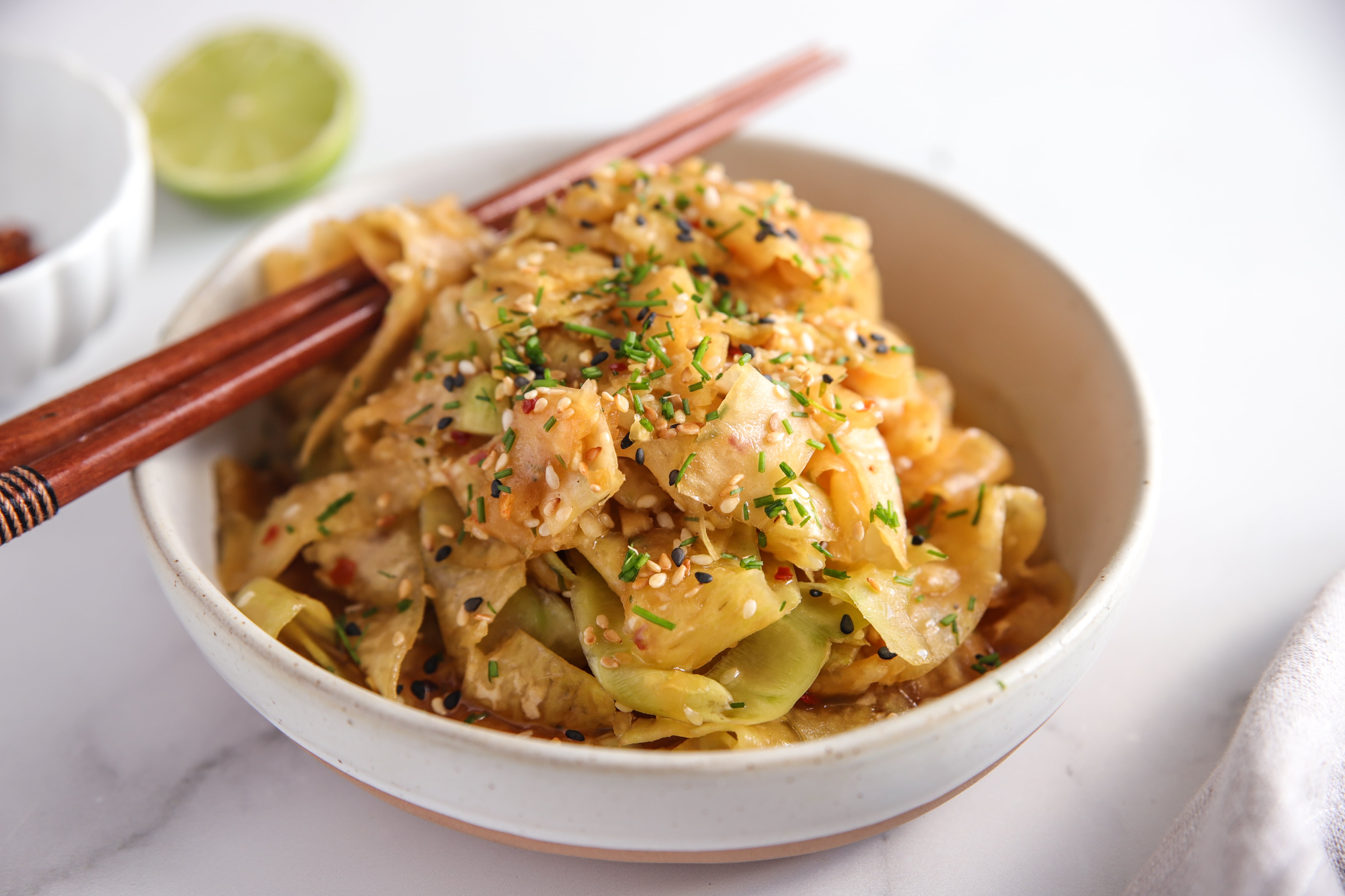 Thinly shaved kohlrabi noodles tossed in sesame–chilli oil, topped with toasted sesame seeds and fresh chives.