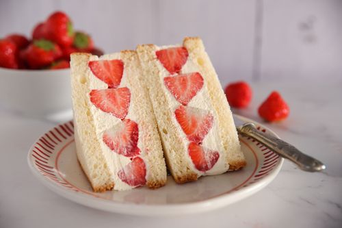 Soft brioche sandwiches filled with whipped cream and whole strawberries, sliced to reveal a perfect fruit cross-section.