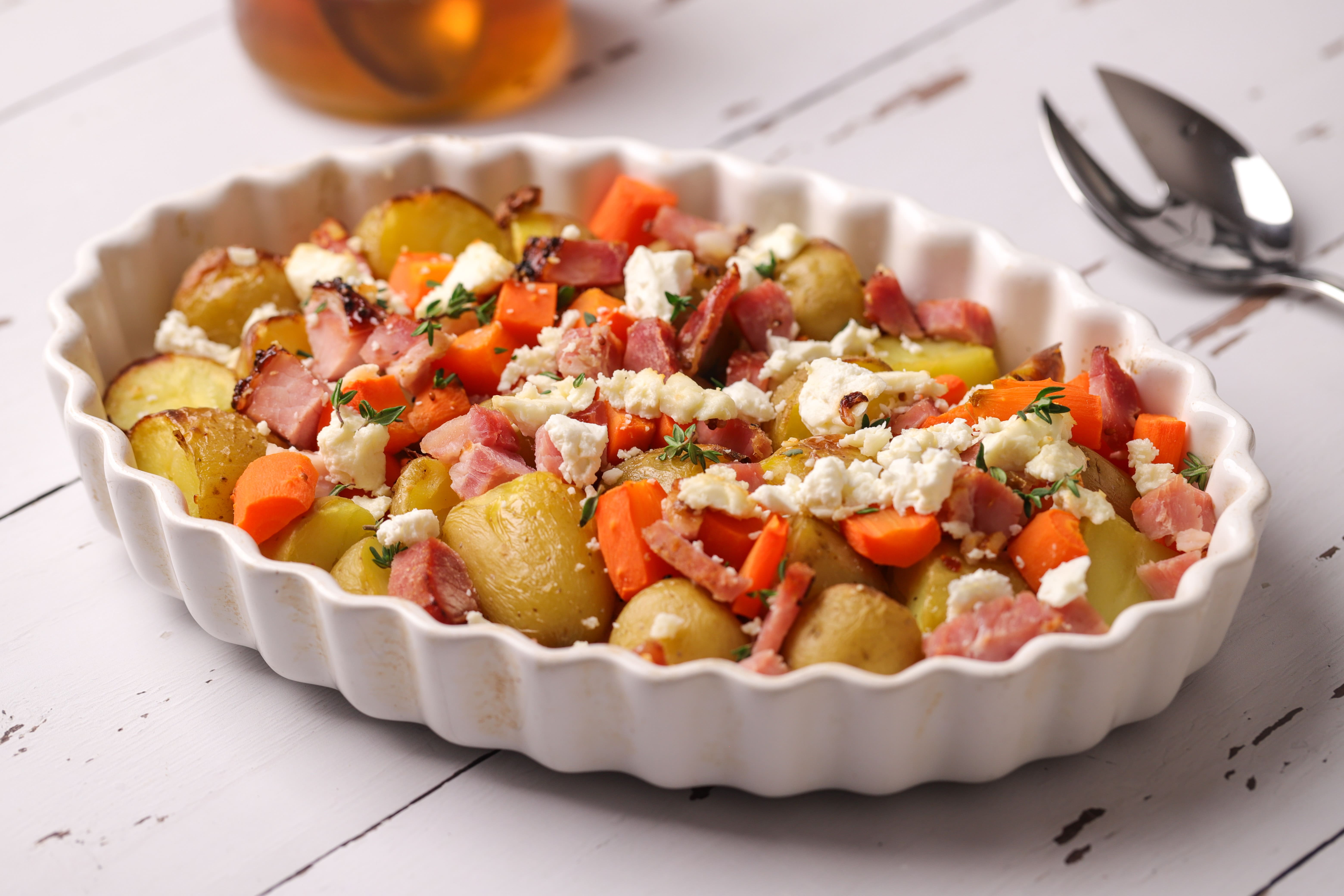 Roasted potato and carrot traybake topped with chopped ham, crumbled feta and a drizzle of hot honey, served straight from the baking dish.