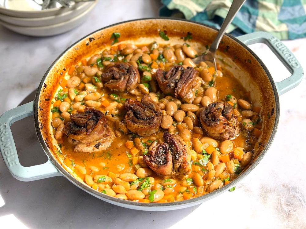 Slow-roasted lamb belly rolls served over creamy butter beans with herbs, lemon and rich pan juices