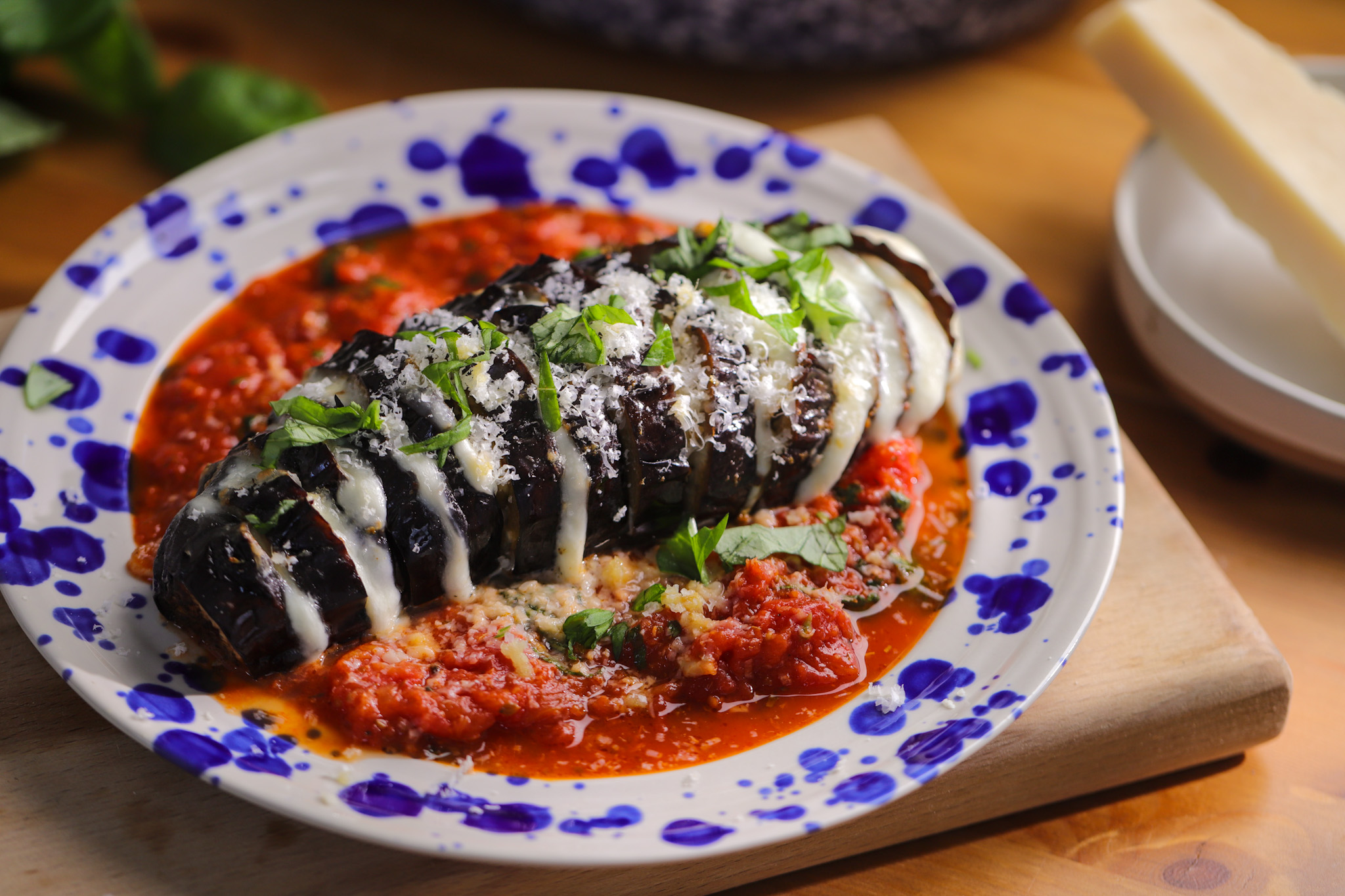 Hasselback eggplant fanned open and stuffed with melted mozzarella, served over a rich tomato sauce and finished with fresh basil and grated parmesan
