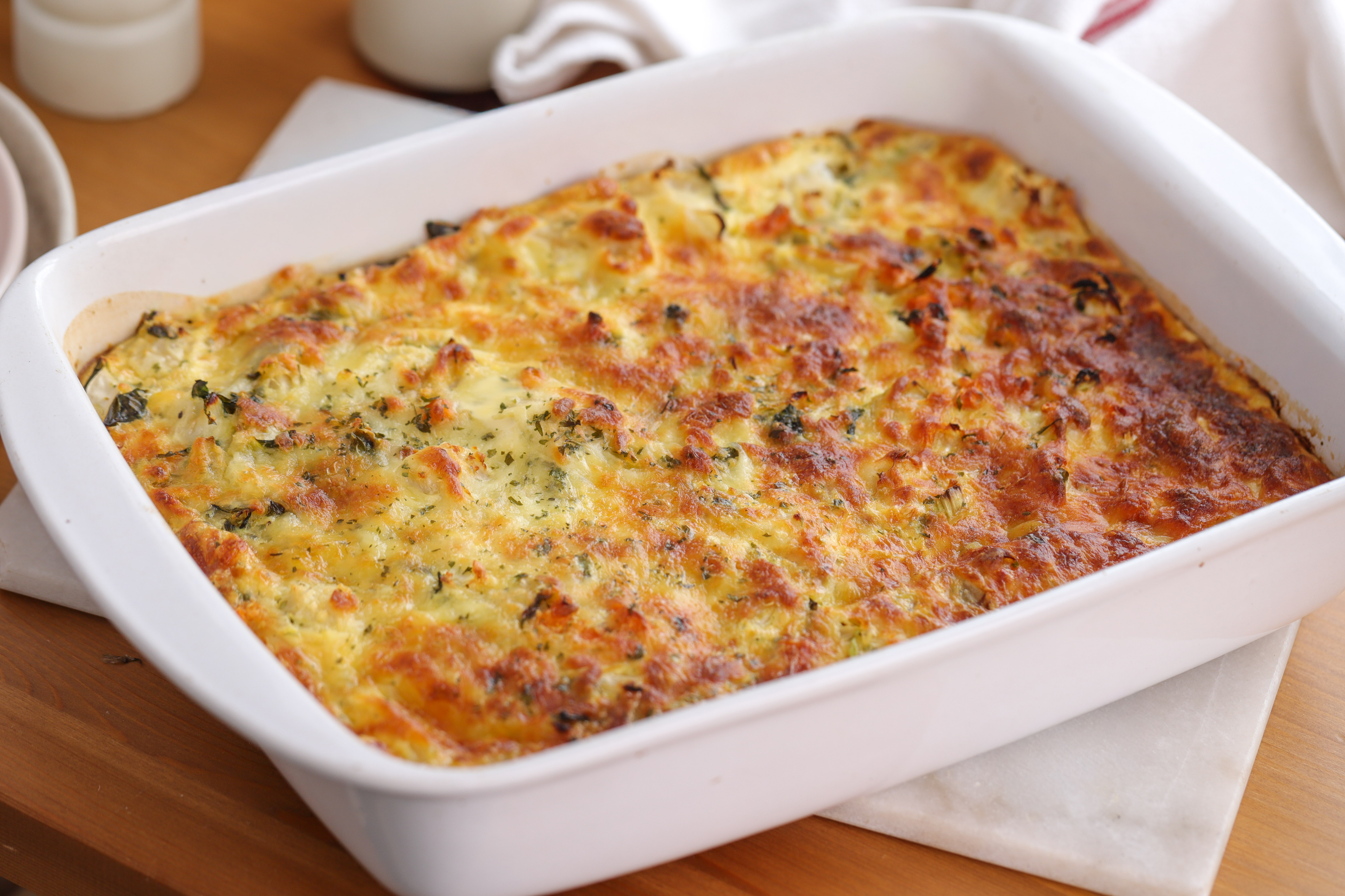 Golden baked cauliflower and carrot bake in a ceramic dish, melted cheese bubbling on top