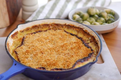Golden baked Brussels sprout and leek gratin in a white ceramic dish, topped with crisp Parmesan breadcrumbs over a bubbling Gruyère cream sauce