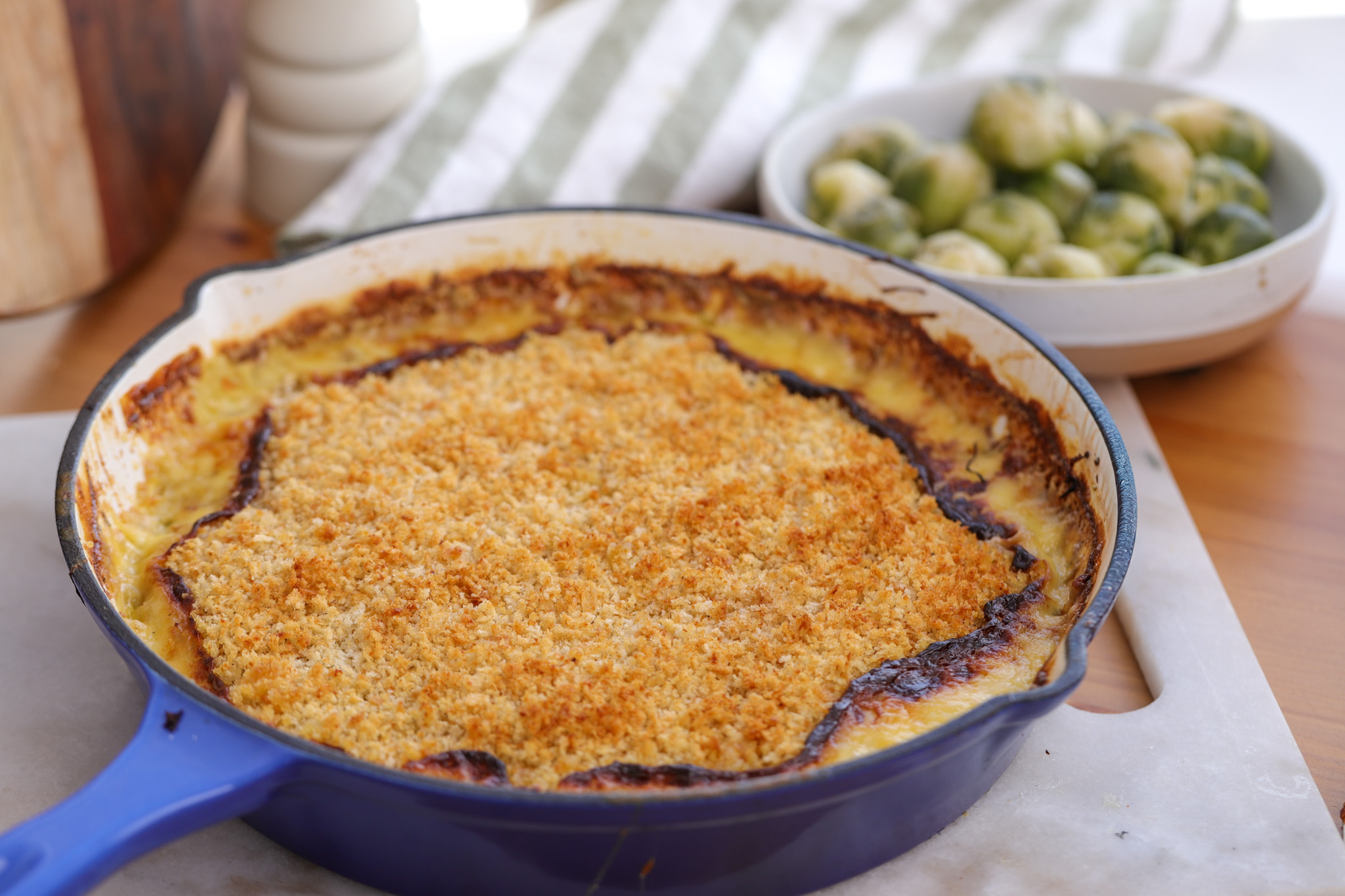 Golden baked Brussels sprout and leek gratin in a white ceramic dish, topped with crisp Parmesan breadcrumbs over a bubbling Gruyère cream sauce