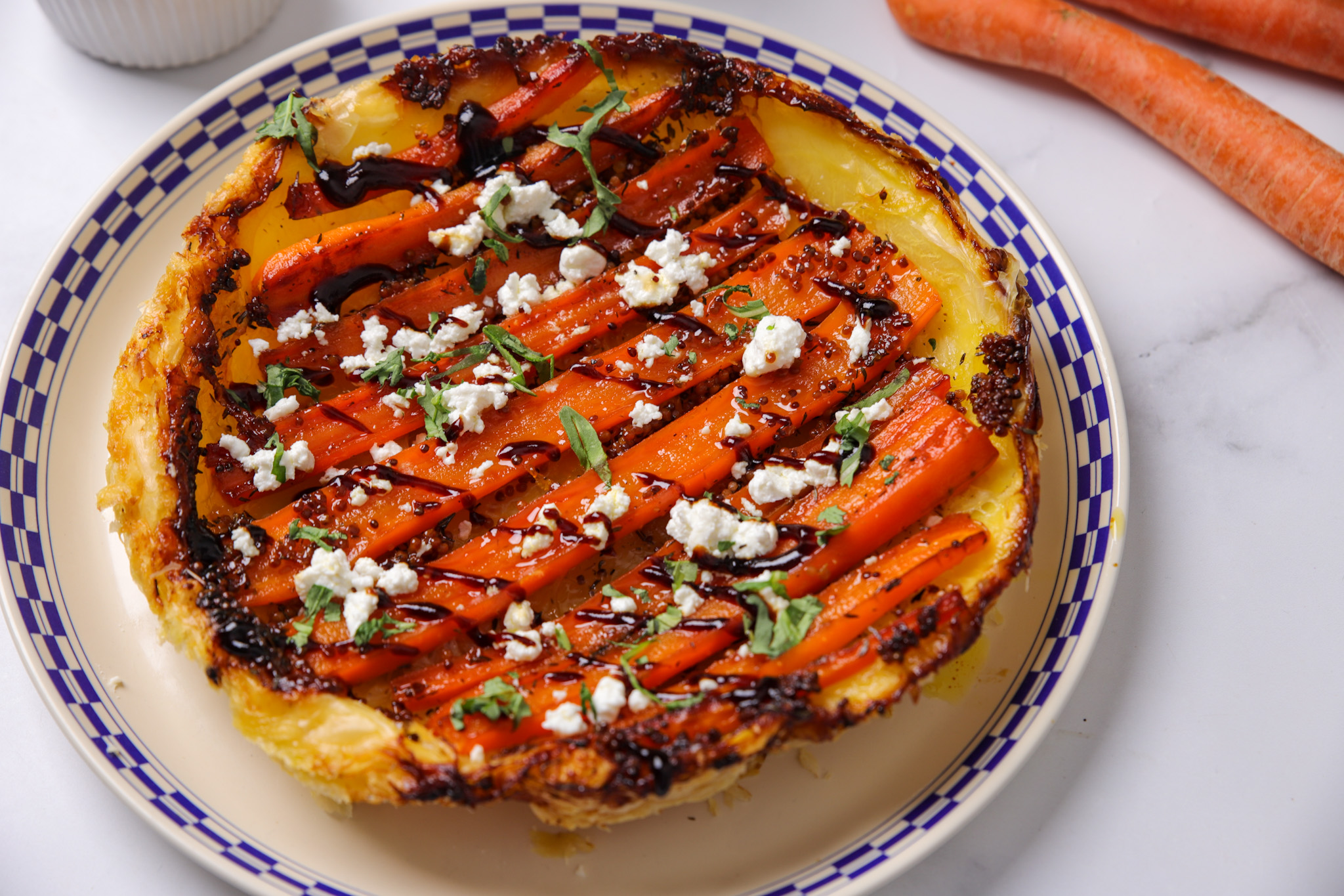 Golden puff pastry tarte tatin topped with sticky caramelised carrots, crumbled goat's cheese and a balsamic drizzle