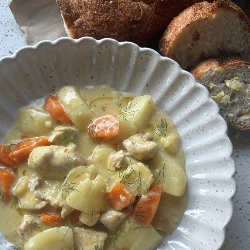 Creamy spring chicken stew with parsnip, carrot and potato in a Dutch oven, topped with fresh dill and a squeeze of lemon
