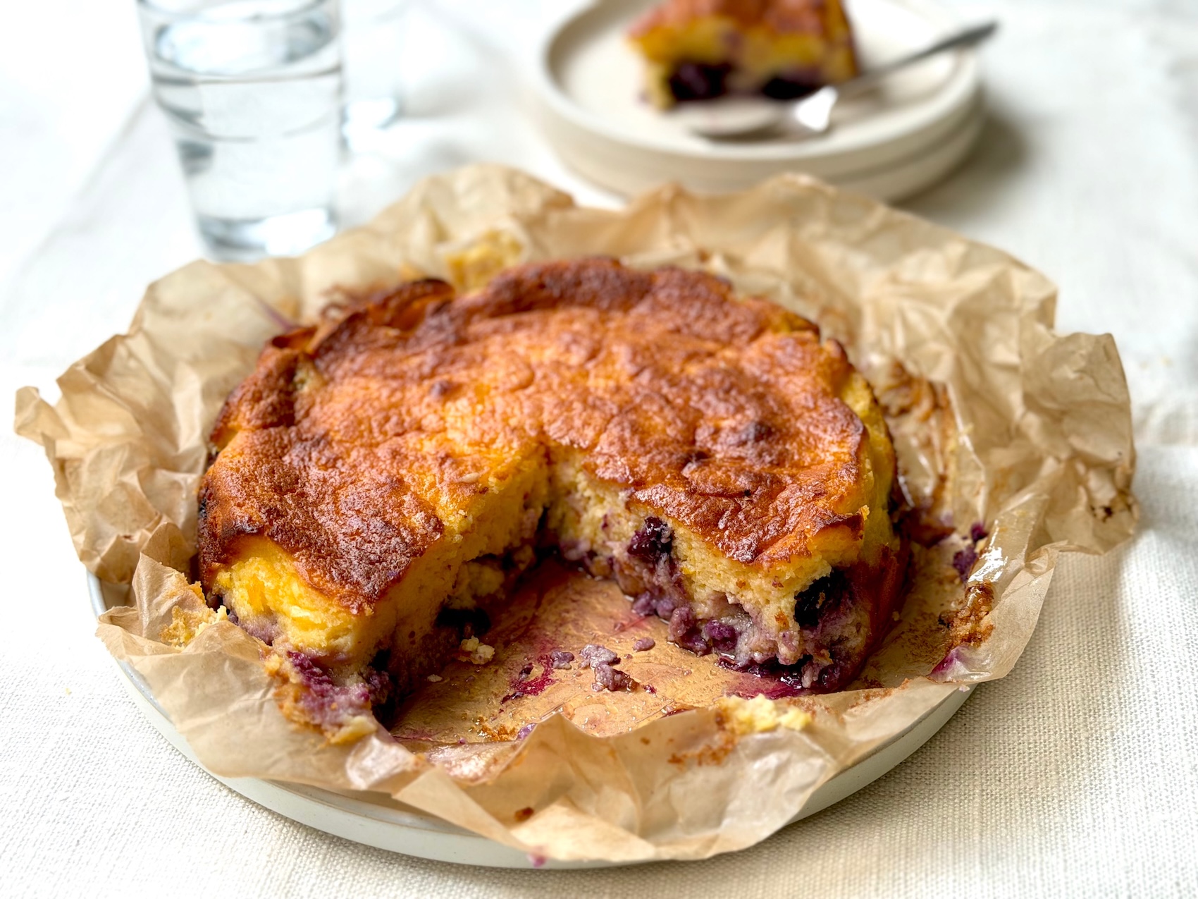 Light blueberry and lemon ricotta cake studded with whole blueberries, one slice cut to show the soft, airy crumb.