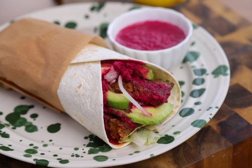 Spiced lamb kebab wrap with avocado, lettuce and beetroot yoghurt sauce, rolled and ready to eat