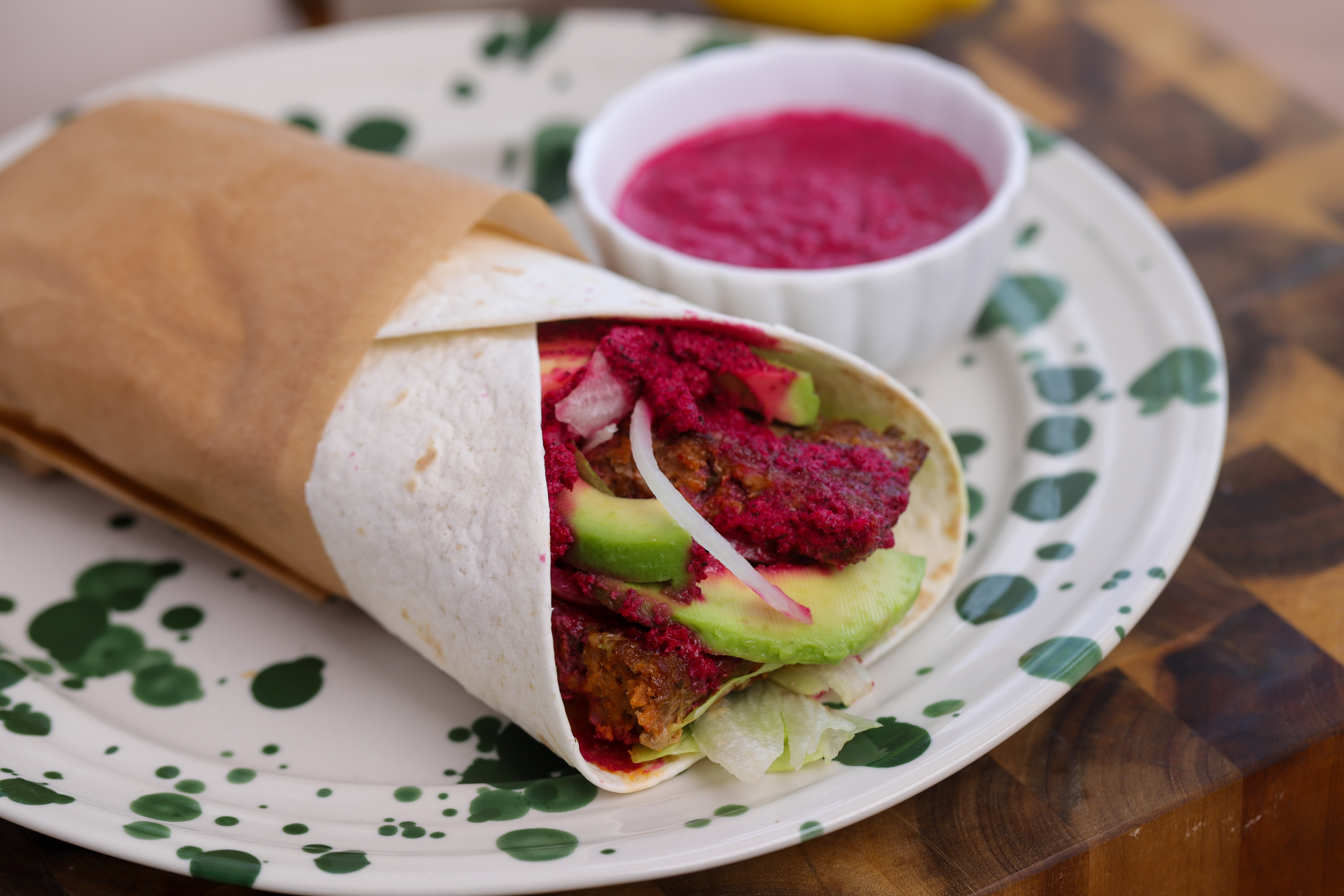 Spiced lamb kebab wrap with avocado, lettuce and beetroot yoghurt sauce, rolled and ready to eat