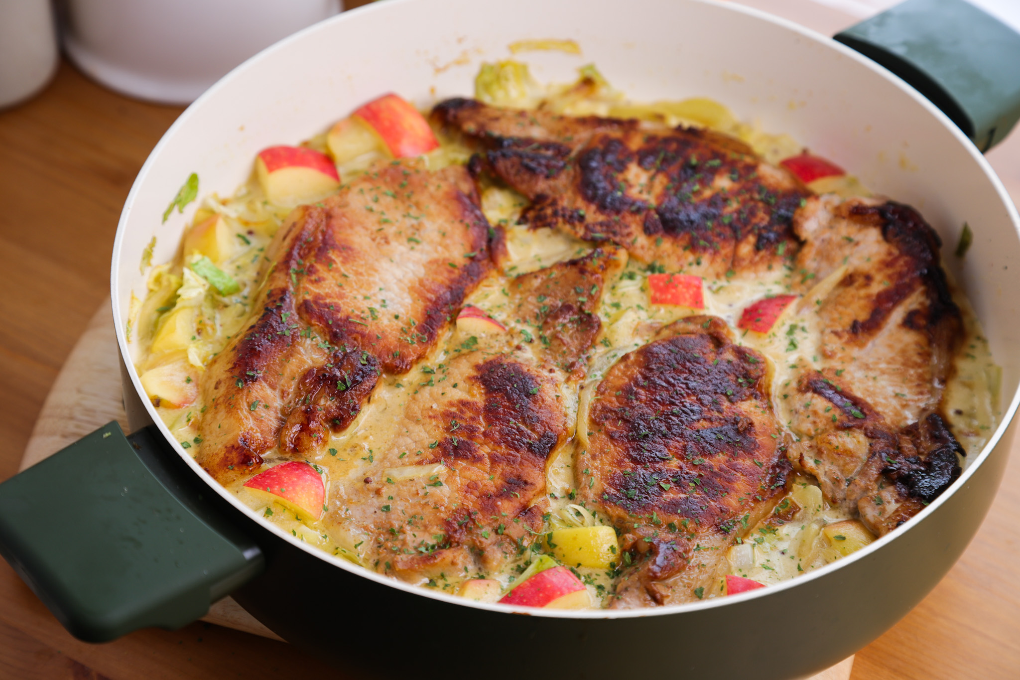 Seared pork loin chops in a creamy sour cream sauce with softened green cabbage, sliced apple and onions, served with mashed potatoes