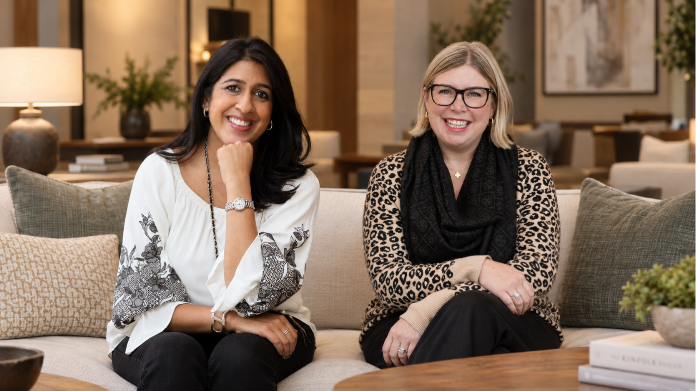 Two women smiling, seated on a sofa
