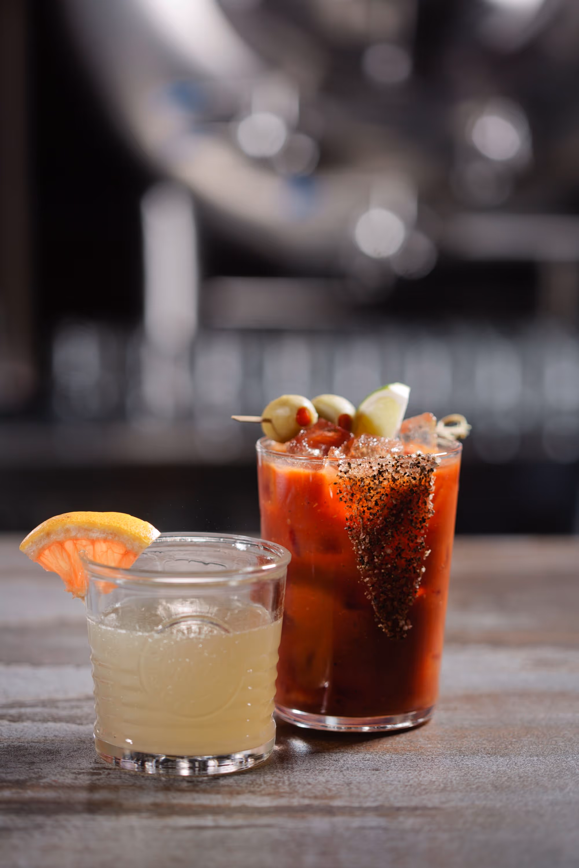 two garnished cocktails on bar counter