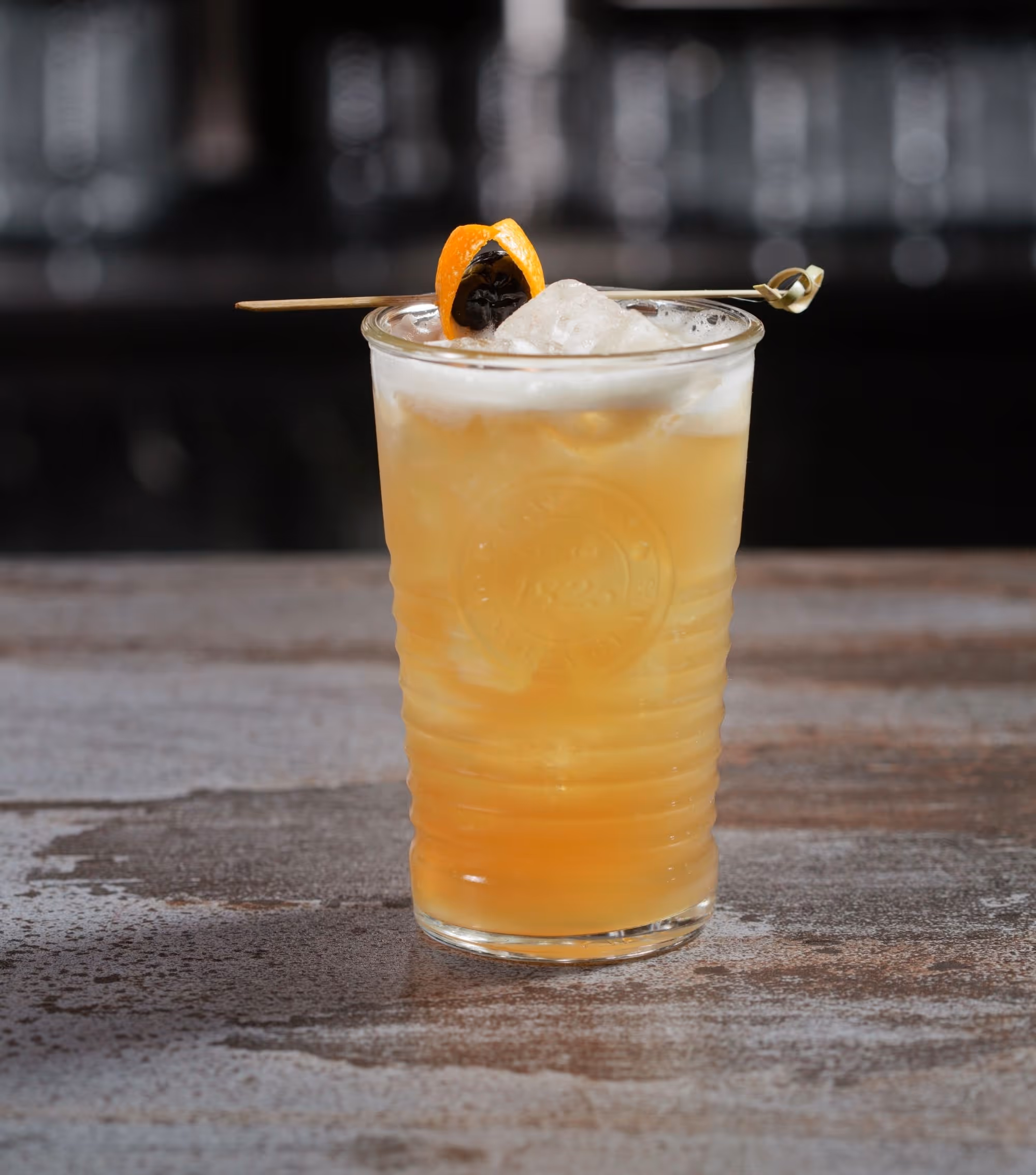 orange cocktail with froth and orange garnish