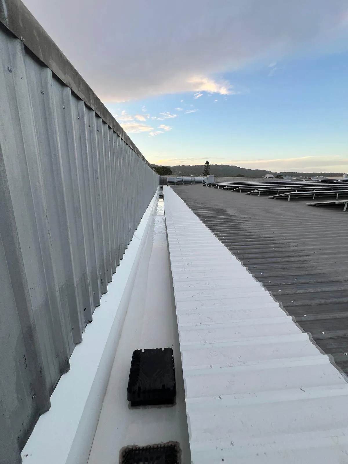 Box gutter replacement at John St, Warners Bay — new full-length box gutter and roof sheeting along the supermarket roofline