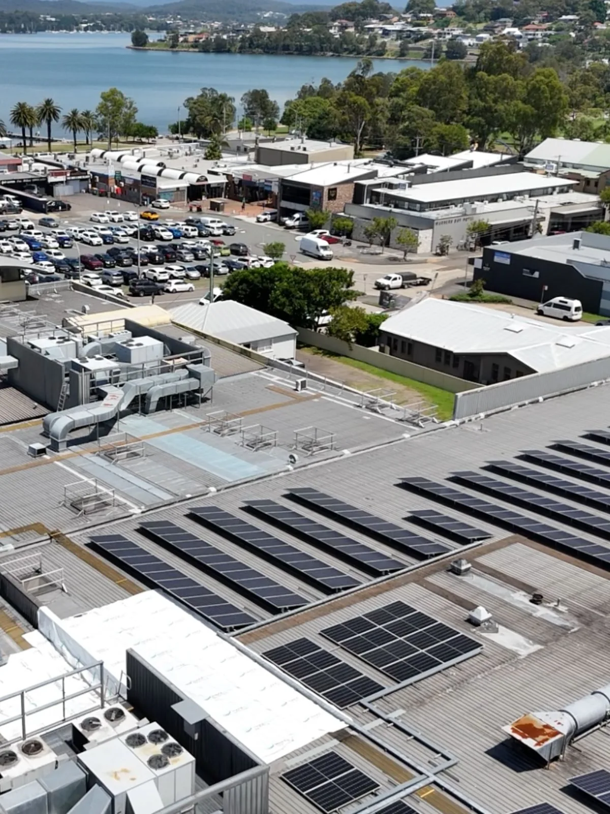 Roof replacement at John St, Warners Bay — aerial view of the 5,000m² supermarket roof and box gutters above the Coles shopping centre