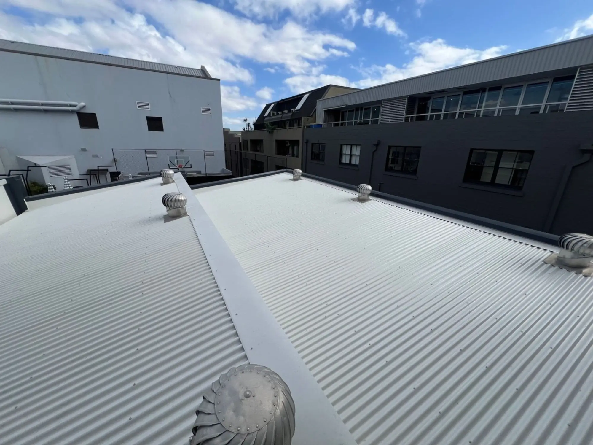 Metal roof replacement at Henrietta St, Chippendale — new corrugated roof sheeting and ventilators across the main roof