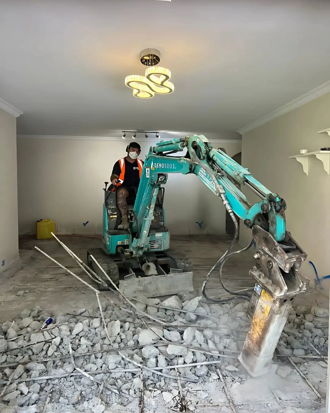 Structural slab remediation at Pacific Hwy, Killara — mini excavator breaking out the failed slab inside the unit