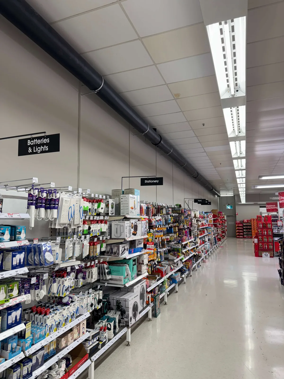 Roof works at John St, Warners Bay — Coles supermarket aisles trading as normal beneath the completed overhead drainage works