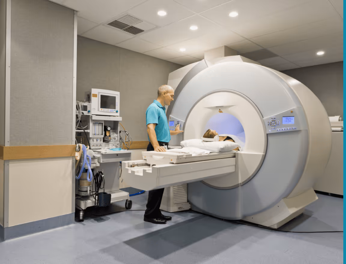 A photograph of a patient in an mri machine with the operator standing nearby. 