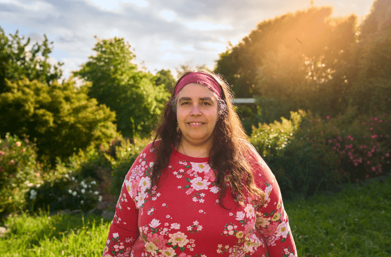 Balkis Sierra, a 50-year-old Australian woman, standing in a field in front of a camera, representing the accessibility and convenience of telehealth in Australia