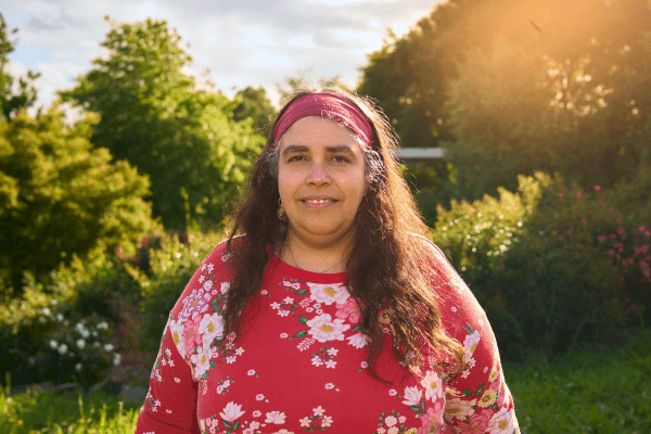 Balkis Sierra, a 50-year-old Australian woman, standing in a field in front of a camera, representing the accessibility and convenience of telehealth in Australia