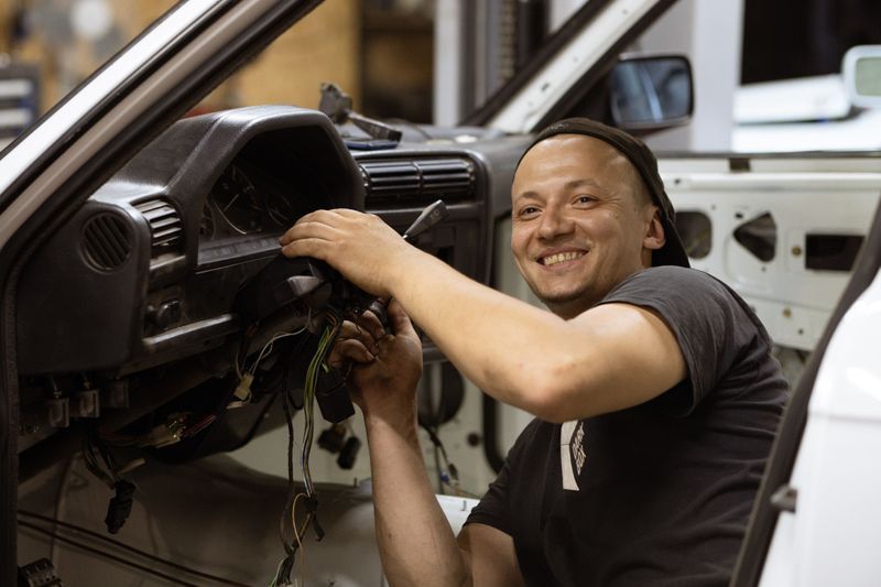 Smiling mechanic working on a car dashboard