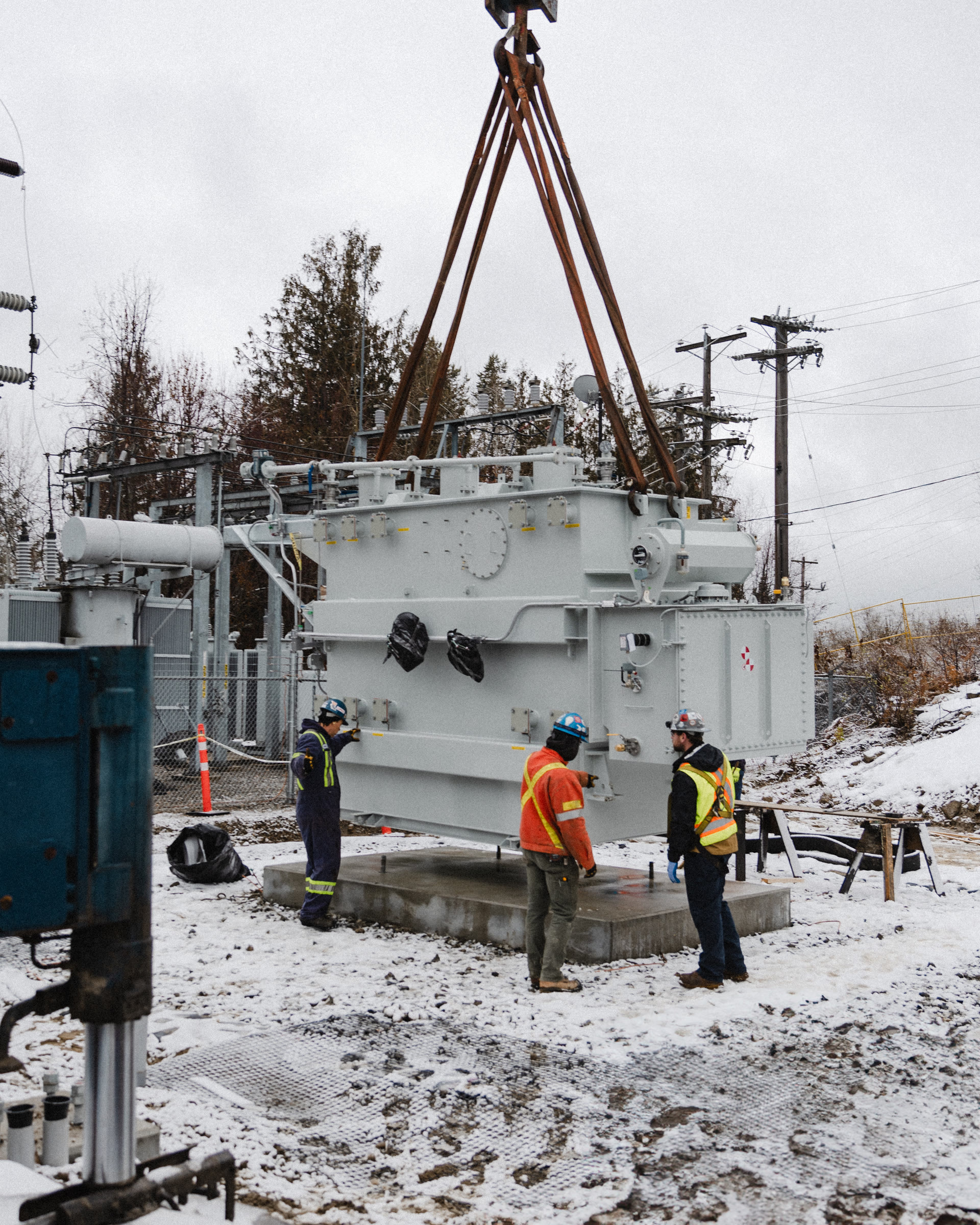 A crane lifting a transformer in winter