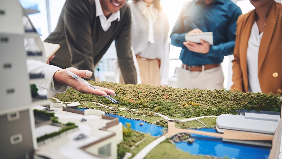 Community members reviewing a detailed scale model of a mixed-use development with green space and waterways