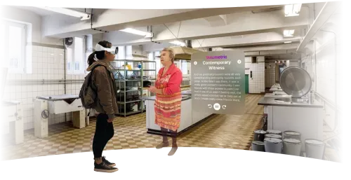 A woman wearing an Apple Vision Pro at an exhibition encountering a volumetric hologram of an elderly lady, who is a contemporary witness