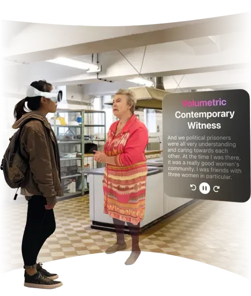 A person wearing an XR headset interacts with a volumetric hologram of an elderly woman sharing a historical narrative in a kitchen setting.