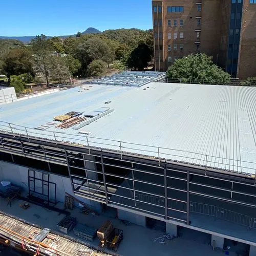 Aerial view of an industrial building with a newly installed metal roof by Element Metal Roofing. The clean, uniform panels reflect high-quality industrial roofing work on a large-scale structure.